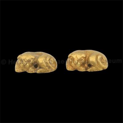 Two identical gold pendants in the shape of a recumbent lion